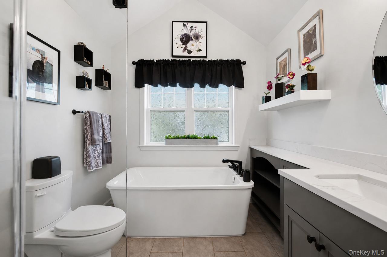 64 Roma Orchard Road Peekskill, NY 10566 - Photo 27 of 40 Bathroom featuring a contemporary freestanding tub, an integrated vanity with a single basin and dark cabinetry, and neutral tile flooring