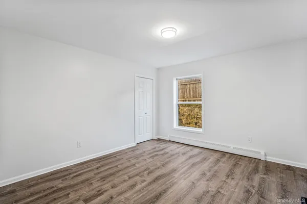 an empty room with wooden floor and window