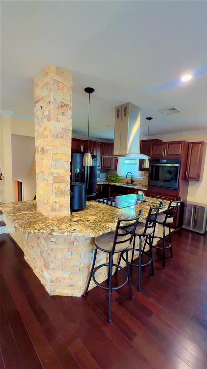 1844 29th Street Southwest Allentown, PA 18103 - Photo 6 of 37 Rich hardwood flooring anchors the open kitchen centered around a stone-faced island breakfast bar.