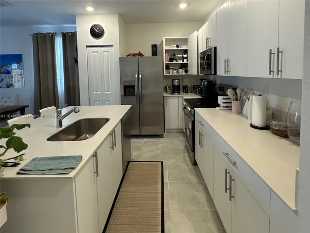 a kitchen with stainless steel appliances granite countertop a sink and a refrigerator