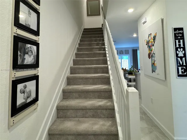 a view of staircase with lots of frames on wall and a painting on the wall