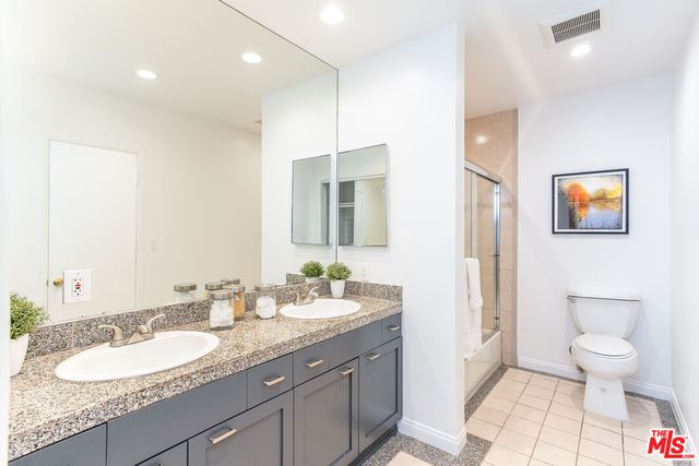 a spacious bathroom with a granite countertop sink a toilet and a mirror
