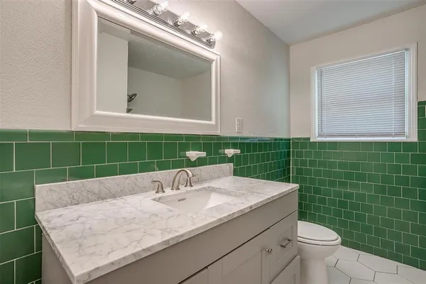 a bathroom with a granite countertop sink a toilet and a mirror