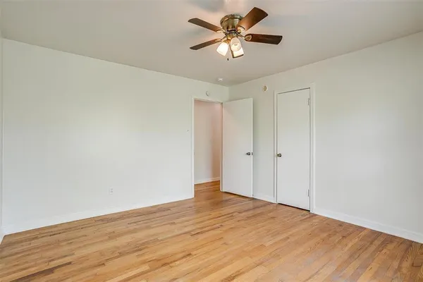 a view of a big room with wooden floor and a chandelier fan