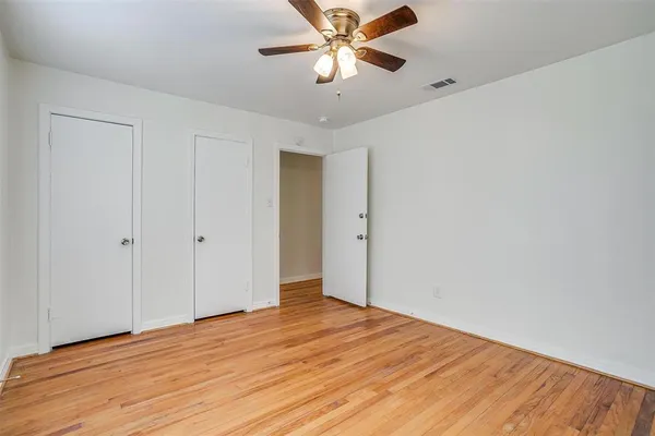 a view of a room with wooden floor and a ceiling fan