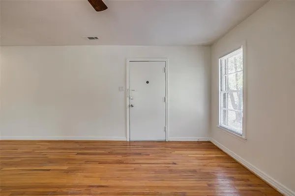 a view of an empty room with window and wooden floor