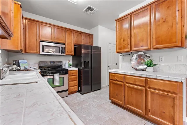 a kitchen with stainless steel appliances granite countertop a refrigerator sink stove microwave and cabinets
