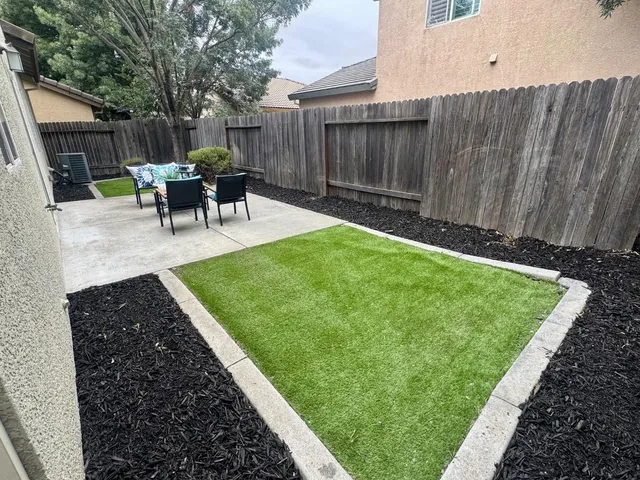 a view of a backyard with table and chairs potted plants and wooden fence