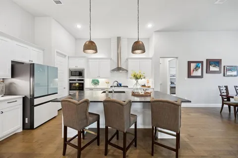 a room with stainless steel appliances kitchen island a table and chairs in it