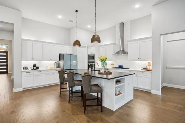 a kitchen with stainless steel appliances granite countertop a sink a stove and a refrigerator