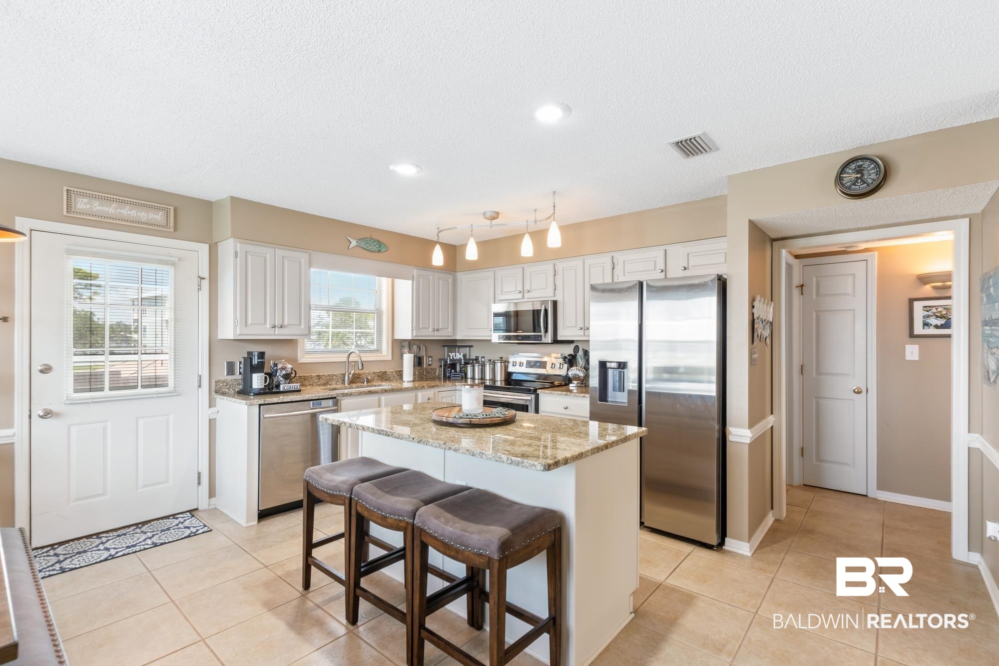 328 Windmill Ridge Road Gulf Shores, AL 36542 - Photo 11 of 47 Kitchen with a textured ceiling, white cabinetry, appliances with stainless steel finishes, a center island, and a breakfast bar area