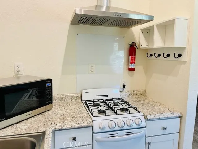 a kitchen with granite countertop a stove and a microwave