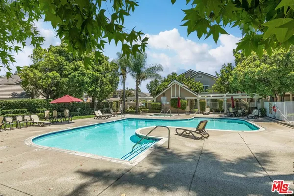 a view of swimming pool with lounge chair and dinning table under an umbrella