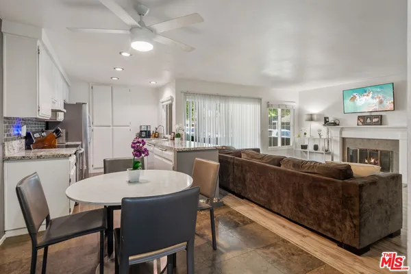 a living room with fireplace furniture and a dining table with kitchen view