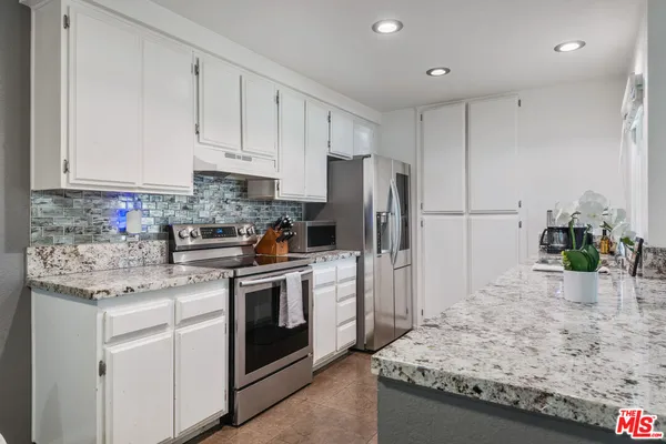 a kitchen with white cabinets and stainless steel appliances