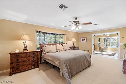 a bedroom with a large bed and a chandelier fan