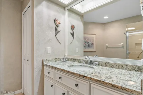 a bathroom with a granite countertop sink a mirror and a shower