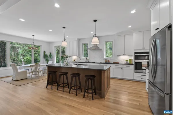 a kitchen with stainless steel appliances granite countertop a refrigerator a sink dishwasher a stove and white countertops with wooden floor