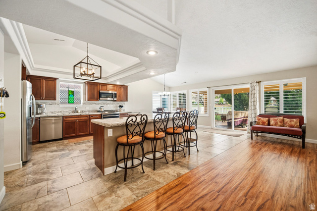 1985 West Rivers Edge Lane St. George, UT 84770 - Photo 40 of 42 Kitchen featuring a chandelier, a kitchen bar, a raised ceiling, stainless steel appliances, and open floor plan