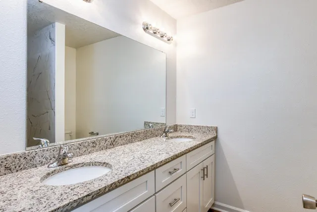 a bathroom with a granite countertop sink and a mirror