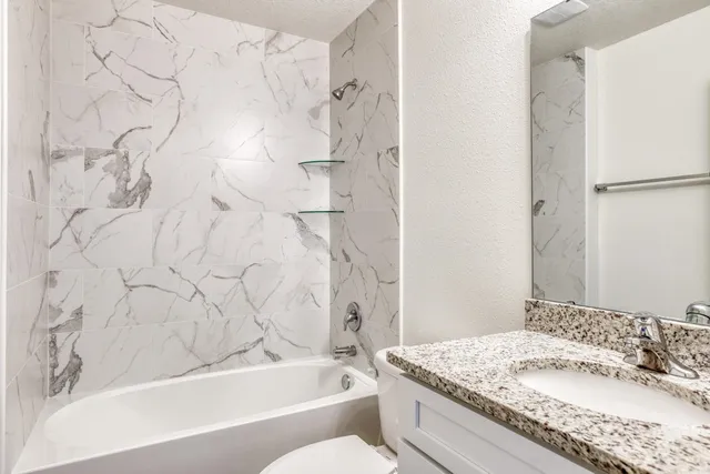 a bathroom with a granite countertop sink toilet and shower