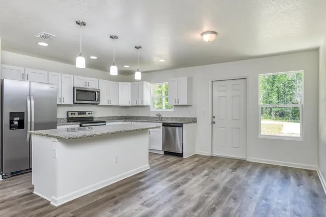 a kitchen with kitchen island granite countertop a sink cabinets and stainless steel appliances