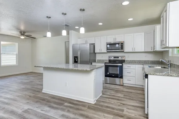 a kitchen with stainless steel appliances granite countertop a stove a sink and a refrigerator