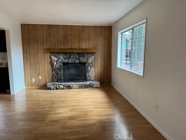 a view of an empty room with wooden floor fireplace and a window