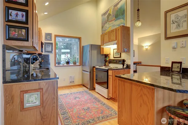 a kitchen with stainless steel appliances granite countertop a sink a stove and a refrigerator