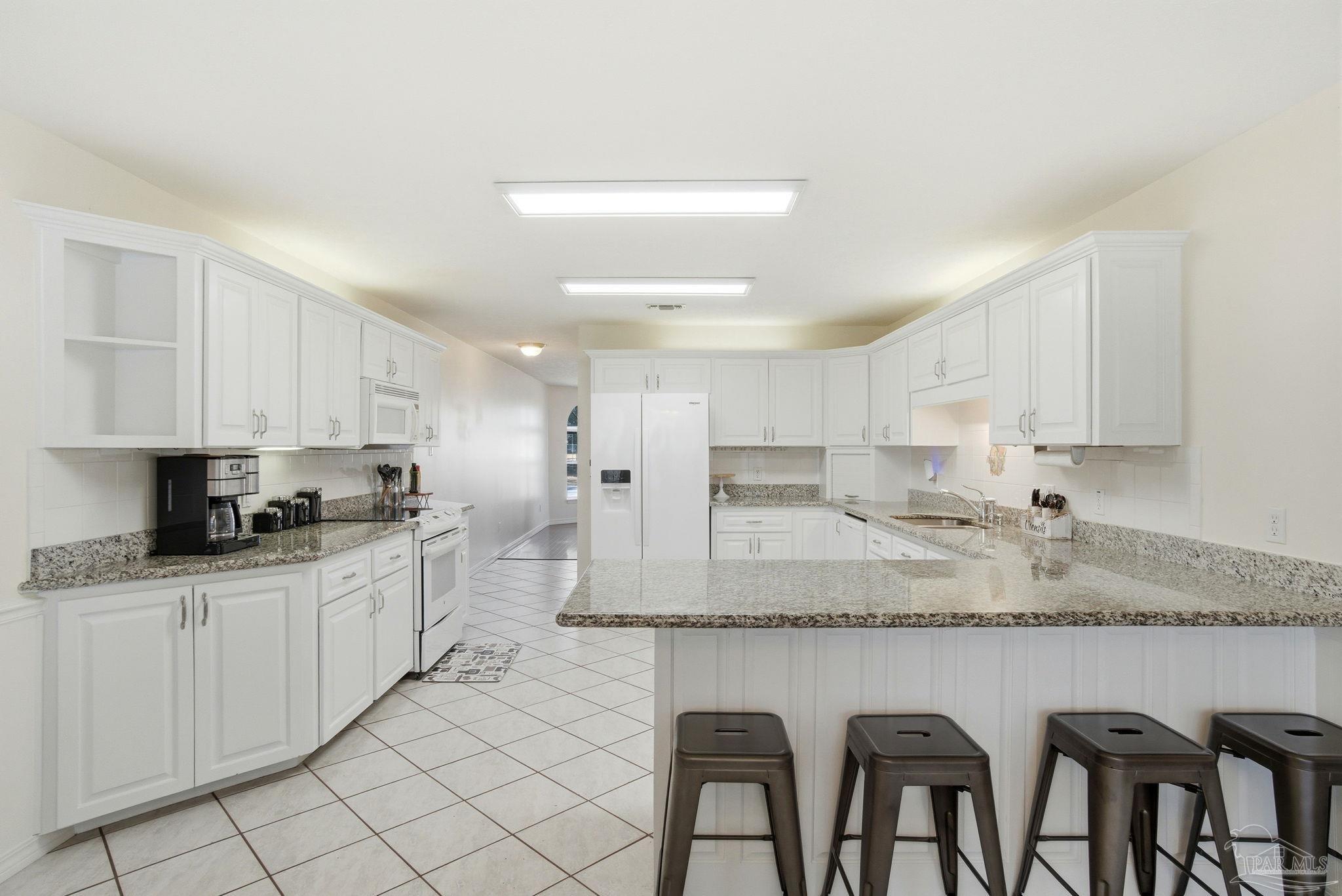1805 West 10 Mile Road Pensacola, FL 32534 - Photo 8 of 61 a kitchen with stainless steel appliances granite countertop a stove a sink a microwave a refrigerator and white cabinets