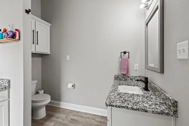 a bathroom with a granite countertop sink and a toilet