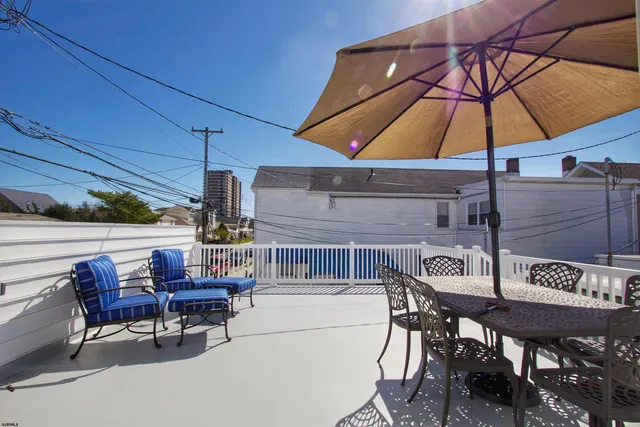 a view of a roof deck with table and chairs under an umbrella