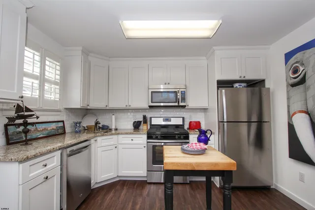 a kitchen with a refrigerator white cabinets and wooden floor