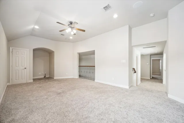 an empty room with chandelier fan and windows