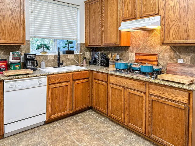 a kitchen with stainless steel appliances granite countertop a sink window and cabinets