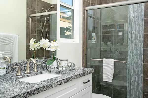 a bathroom with a granite countertop sink a mirror and shower