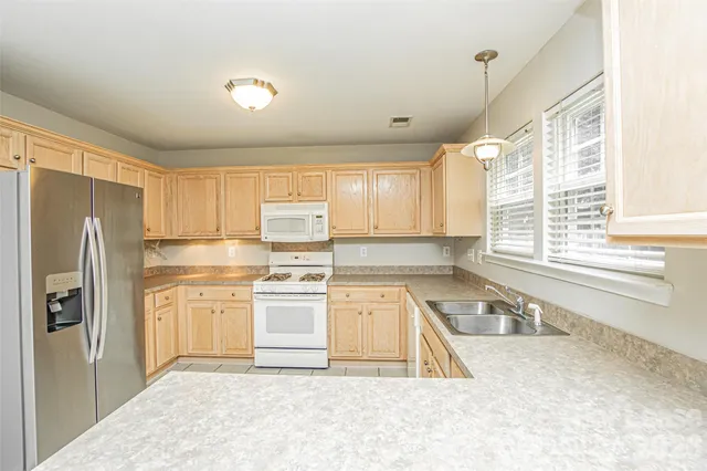 a kitchen with a refrigerator a stove a sink cabinets and a window