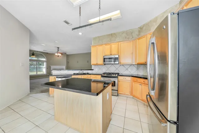 a kitchen with stainless steel appliances granite countertop a sink a stove and a refrigerator