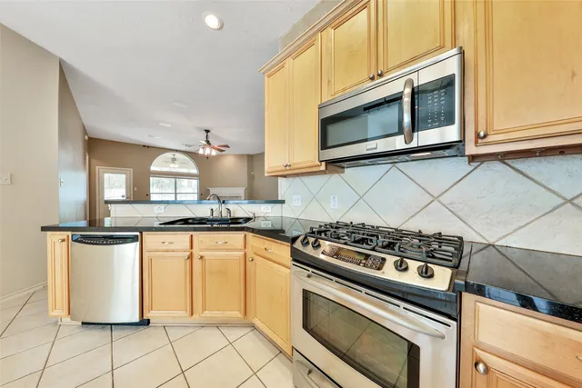 a kitchen with granite countertop a stove top oven microwave and cabinets