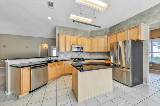 a kitchen with stainless steel appliances granite countertop a refrigerator a sink a stove a microwave and island