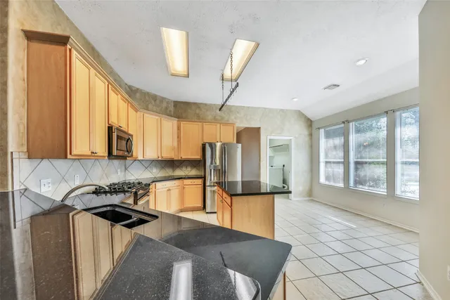 a kitchen with stainless steel appliances granite countertop a sink a stove counter space and cabinets