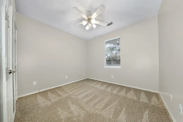 an empty room with windows and chandelier fan