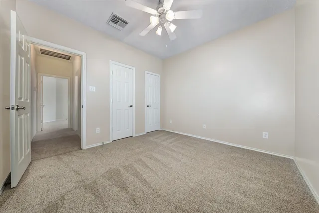 a view of an empty room and chandelier fan
