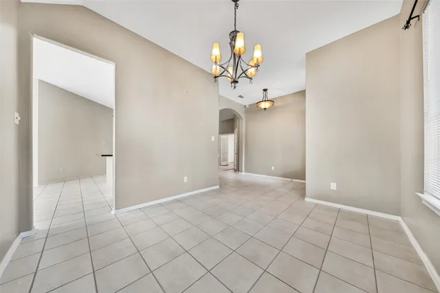 a view of an empty room with a chandelier fan