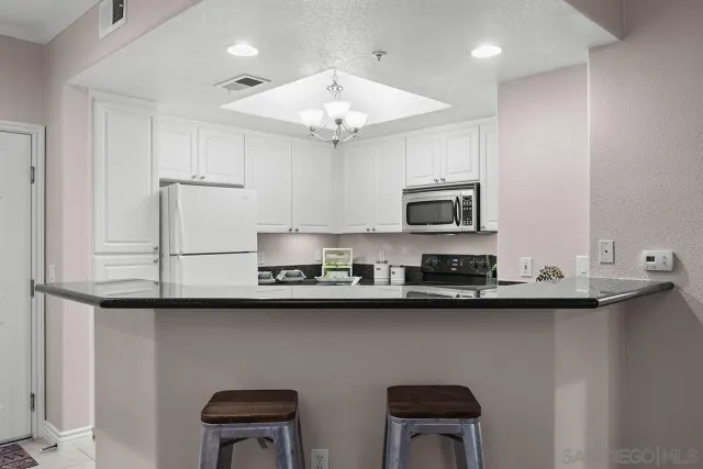 a kitchen with granite countertop white cabinets and black appliances