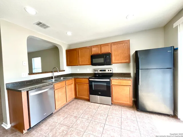 a kitchen with stainless steel appliances granite countertop a refrigerator and a stove top oven