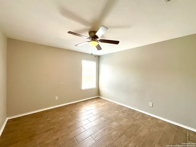 an empty room with a window and a ceiling fan