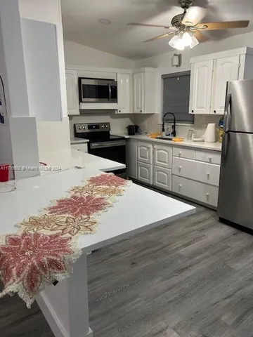 a kitchen with kitchen island granite countertop a stove top oven a refrigerator a sink and dishwasher with wooden floor