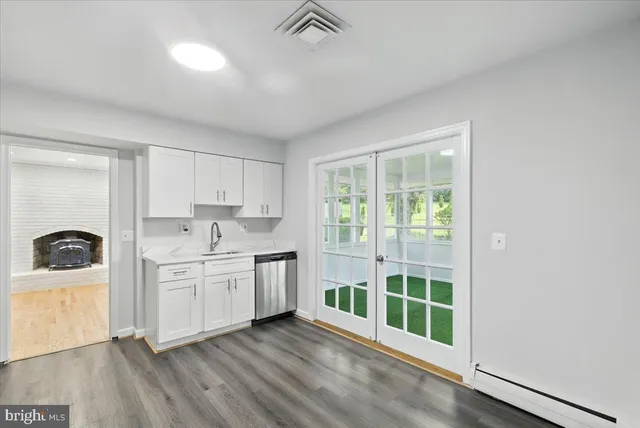 a kitchen with stainless steel appliances granite countertop a stove a sink and a refrigerator with white cabinets