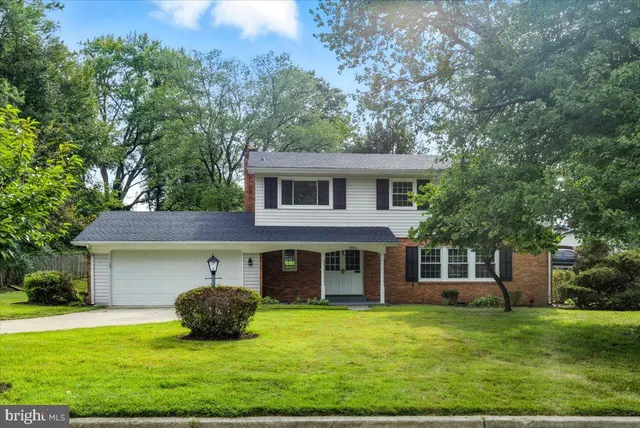 a view of a house with a yard and a large tree